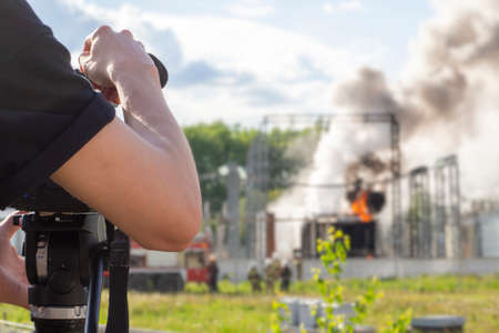 Videographer shoots a fire at an electrical substation on a video camera. Journalist stringer films...