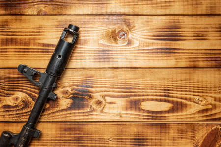 Automatic assault rifle on a wooden table background close-up. Modern black assault gun.の写真素材