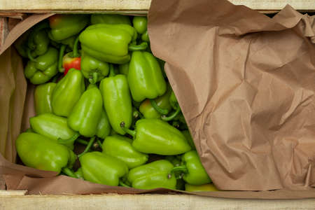 Green bell pepper in a wooden box with package packaging, top view. The concept of delivery of goods...