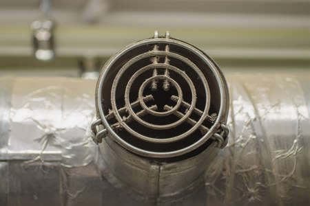 An old metal ventilation pipe with a dusty grate.