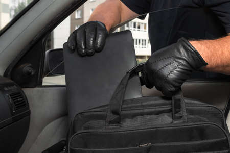Thief steals a laptop bag from the passenger seat from an open car window. View from inside the...
