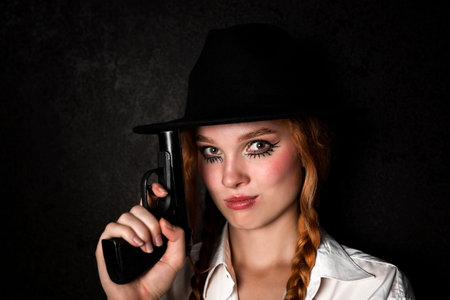 A mafia woman in a white shirt with a bowler hat holds a gun in her hands. Portrait of a gangster...