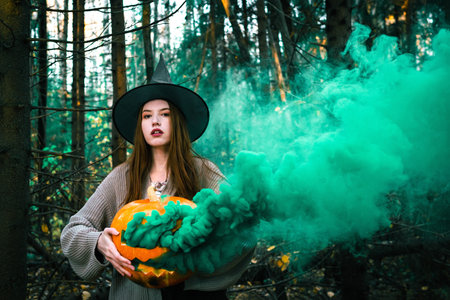 A witch woman in a black hat in the autumn forestの写真素材