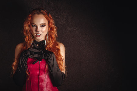 A red haired girl in black evening gloves with a pink corset and a bow tie on a dark background....