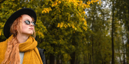 Portrait of a red haired woman in black glasses and a black hat in an orange scarf on the background...