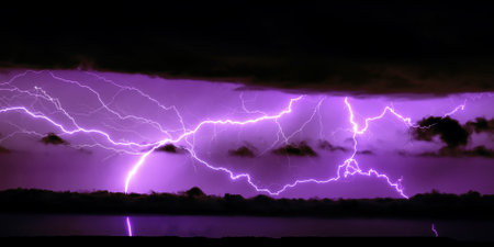 Purple or blue horizontal lightning in the night sky in black clouds. A real photo of a thunderstorm. The concept of meteorology.の写真素材