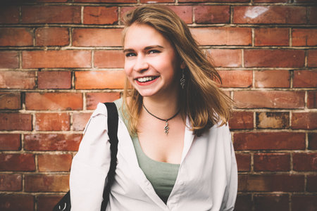 Happy woman portrait in a white shirt on the background of the exterior of the brick wall of the...
