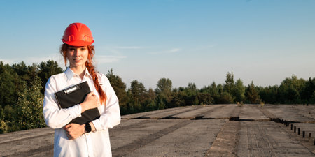 Portrait of a female construction inspector in a white shirt and a red hard hat on the background of a bridge being built.の写真素材