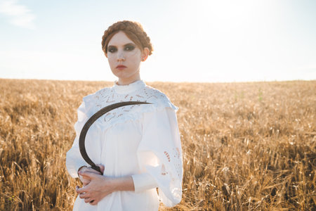 Slavic girl in a white dress and a black skirt with witch makeup stands in a field of rye and holds...