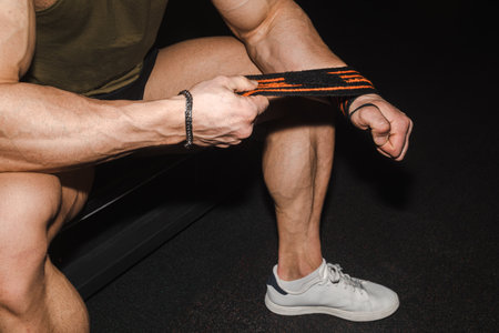 Athlete man wraps gymnastic bandages around his wrists. Hands of an unrecognizable sportsman in close up. The concept of preparing for a workout or strength exercise.の写真素材