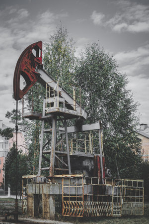 Deserted oil well with pumpjack. Abandoned gas rocking machine on the outskirts of the city. Concept of a resource crisis.の写真素材