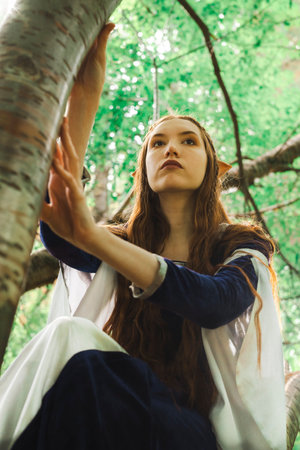 Portrait of a female elf warrior in a blue dress and red hair in the forest.の写真素材