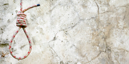 Gallows noose suspended from a rope knot against the background of a cement wall.の写真素材
