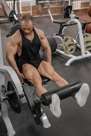 Male bodybuilder on the exercise machine for legs in the gym. Concept of a healthy lifestyle