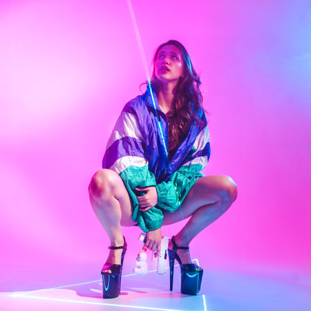 Cyberpunk woman on high heels with a pink pistol in a sports jacket in laser lighting on a neon background.の写真素材