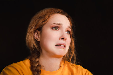 Young woman with a fearful expression, wide eyes, and tense lips, showing anxiety and worry.