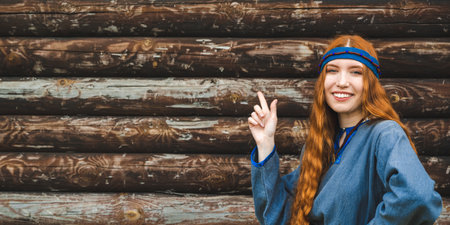 Red haired woman with freckles in a blue linen medieval dress against the background of a wooden...