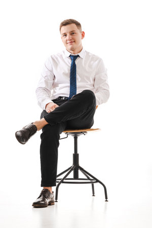 25 years man in a white shirt and blue tie sits on a chair. Concept of formal corporate photographyの写真素材