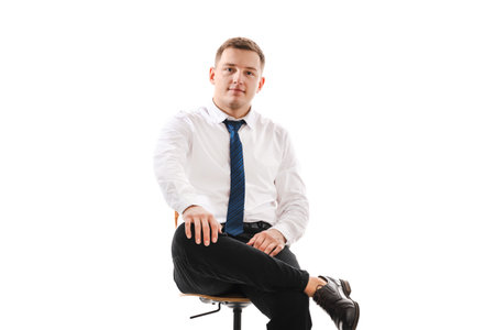 25 years man in a white shirt and blue tie sits on a chair. Concept of formal corporate photographyの写真素材