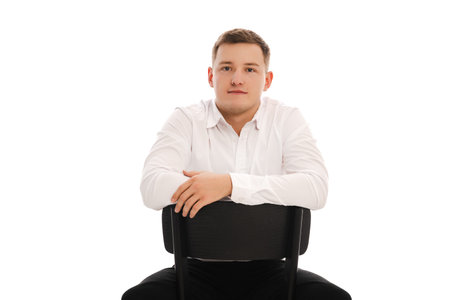 25 years man in a white shirt and blue tie sits on a chair. Concept of formal corporate photographyの写真素材