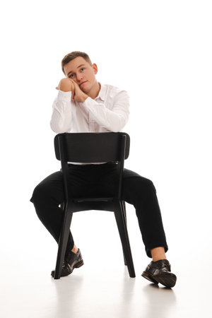 25 years man in a white shirt and blue tie sits on a chair. Concept of formal corporate photographyの写真素材