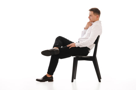 25 years man in a white shirt and blue tie sits on a chair. Concept of formal corporate photographyの写真素材