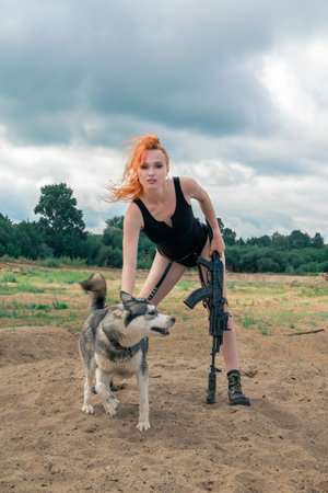 Red haired woman in a black bodysuit with a husky dog in the sand.の写真素材