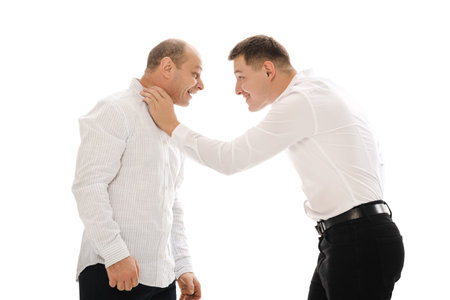 Two people on white background in a physical confrontation, gripping each other, wearing white shirts.の写真素材