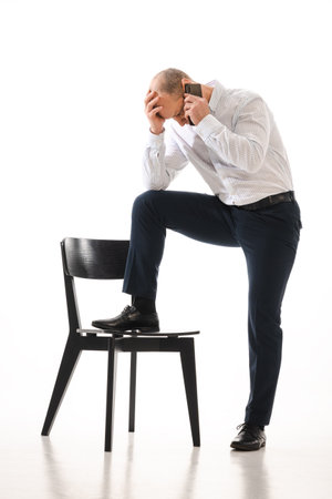 Stressed 50 year old man call or smartphone, photo isolated on white background.の写真素材