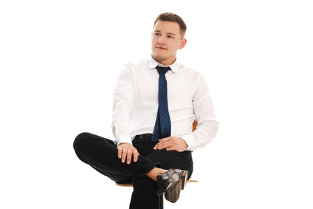 25 years man in a white shirt and blue tie sits on a chair. Concept of formal corporate photographyの写真素材