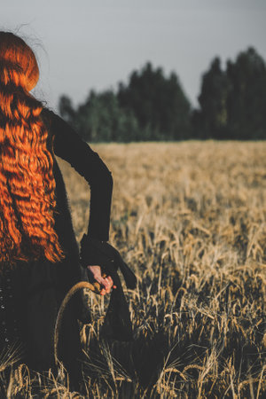 Hooded woman with a scythe stands in a field, exuding a mystical and eerie vibe, suggesting a ritual or witchcraft.の写真素材