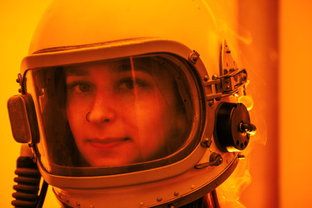 Woman in an astronaut helmet, with smoke emerging, stands against a bright orange background,...