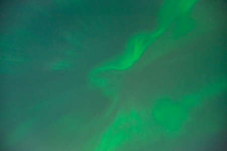 Coronal aurora borealis glowing in the night sky, vibrant green color lights.の写真素材