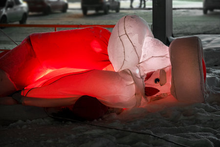 Deflated inflatable Santa Claus, collapsed holiday decoration, snow-covered, winter scene, broken Christmas display.の写真素材