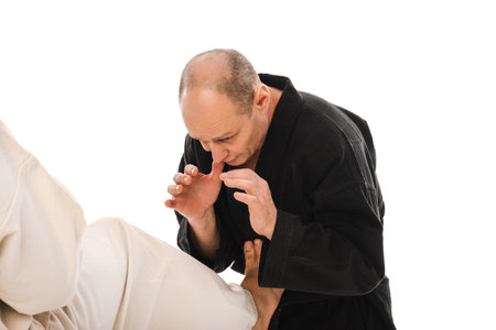 Two martial artists practicing karate, one delivering a high kick, wearing black and white kimono. First-person view.の写真素材