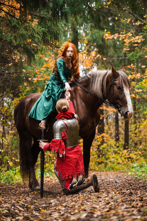 Knight in armor holding a princess hand on horseback in a magical autumn forest.の写真素材