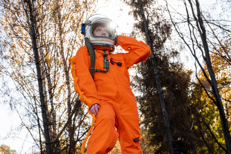 Astronaut in an orange suit on the ruins of a burnt-out building. The charred remains of a wooden house at the site.の写真素材