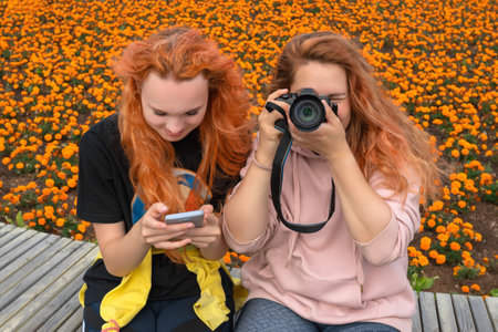 Two red-haired friends, a photographer and a model, pose in a city park.の写真素材