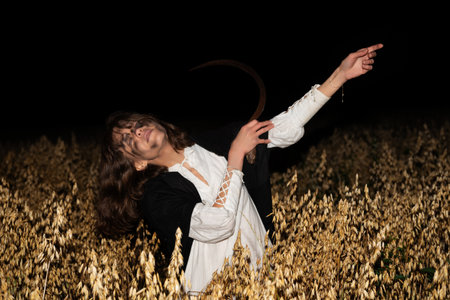 Woman in a white dress holding a sickle stands in a field of dry oats at night, with a menacing and...