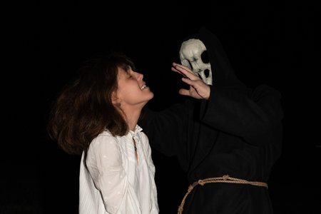 Woman in a long white dress stands in a field at night with her hands tied by a rope, accompanied by...