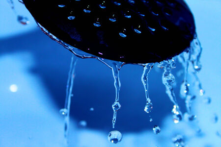 Water running on the perforated spoonの写真素材