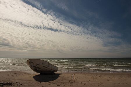 Stunning sky over a fishing boat on Baltic beach in Ventspilsの写真素材