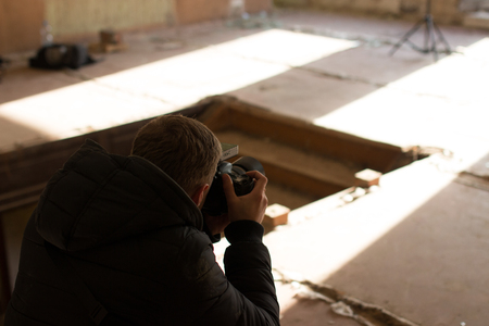 Photographer in motion, doing a photo shoot indoorsの写真素材