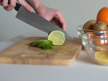 Woman cutting the lime into thin pieces on wooden board for making a drinkの写真素材