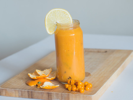 Healthy orange smoothie with orange and sea-buckthorn on the wooden boardの写真素材