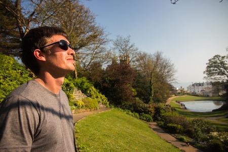 Man in black sunglasses looking at the sun in amazing park. Looking in the futureの写真素材