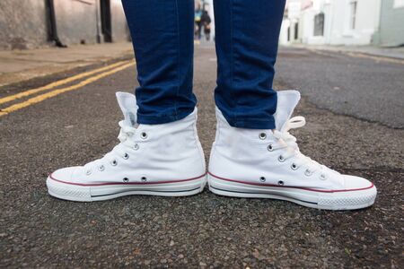 Close-up of female feet in fashionable sneakers are standing on the sidewalk.の写真素材
