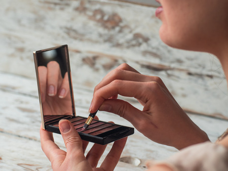 Close up photo of woman lips with lipstick in hand. Makeup artist. Creative make up artist.の写真素材