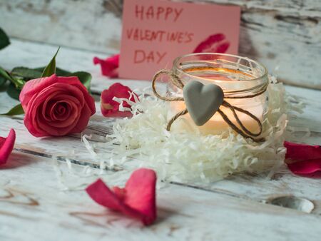 Burning candle and rose petals on vintage wooden table. Valentines Day and Mothers Day background.の写真素材