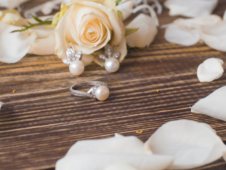 Pearl ring and earrings with white rose on dark wooden background, close upの写真素材